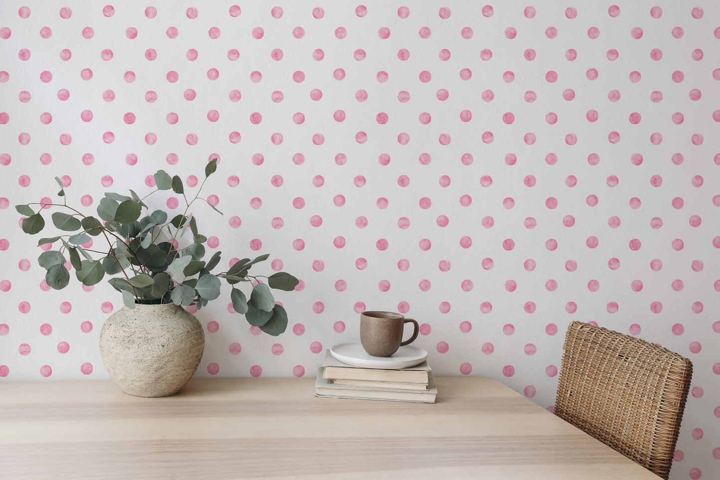 Study space wallpaper with pink dots behind a wooden table and green plant.