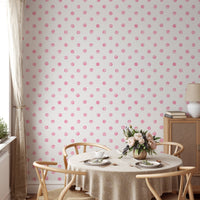 Pink watercolor dots wallpaper in a dining area with a round table and beige chairs.