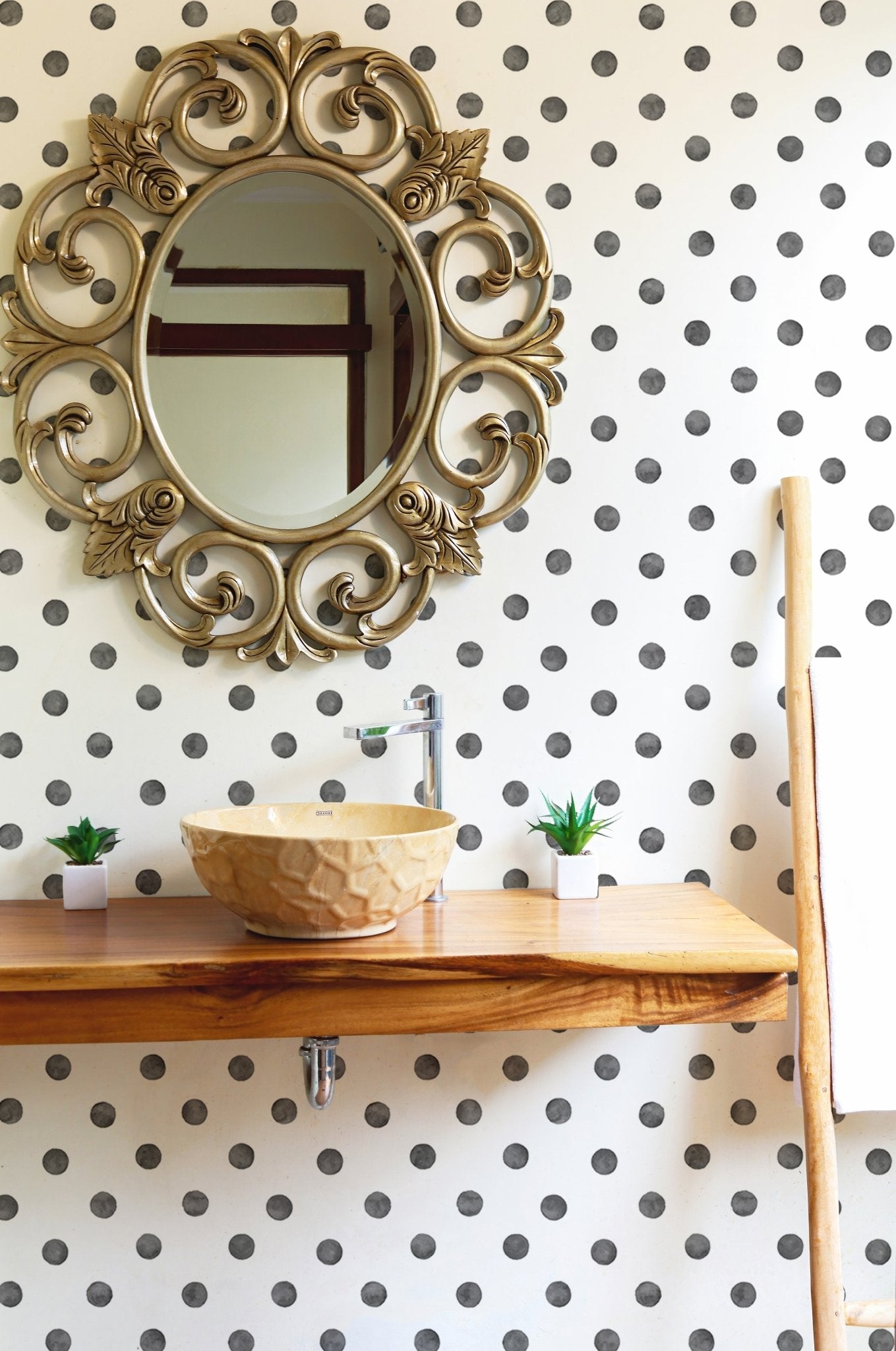 Bathroom vanity with a round mirror and watercolor dot wallpaper.