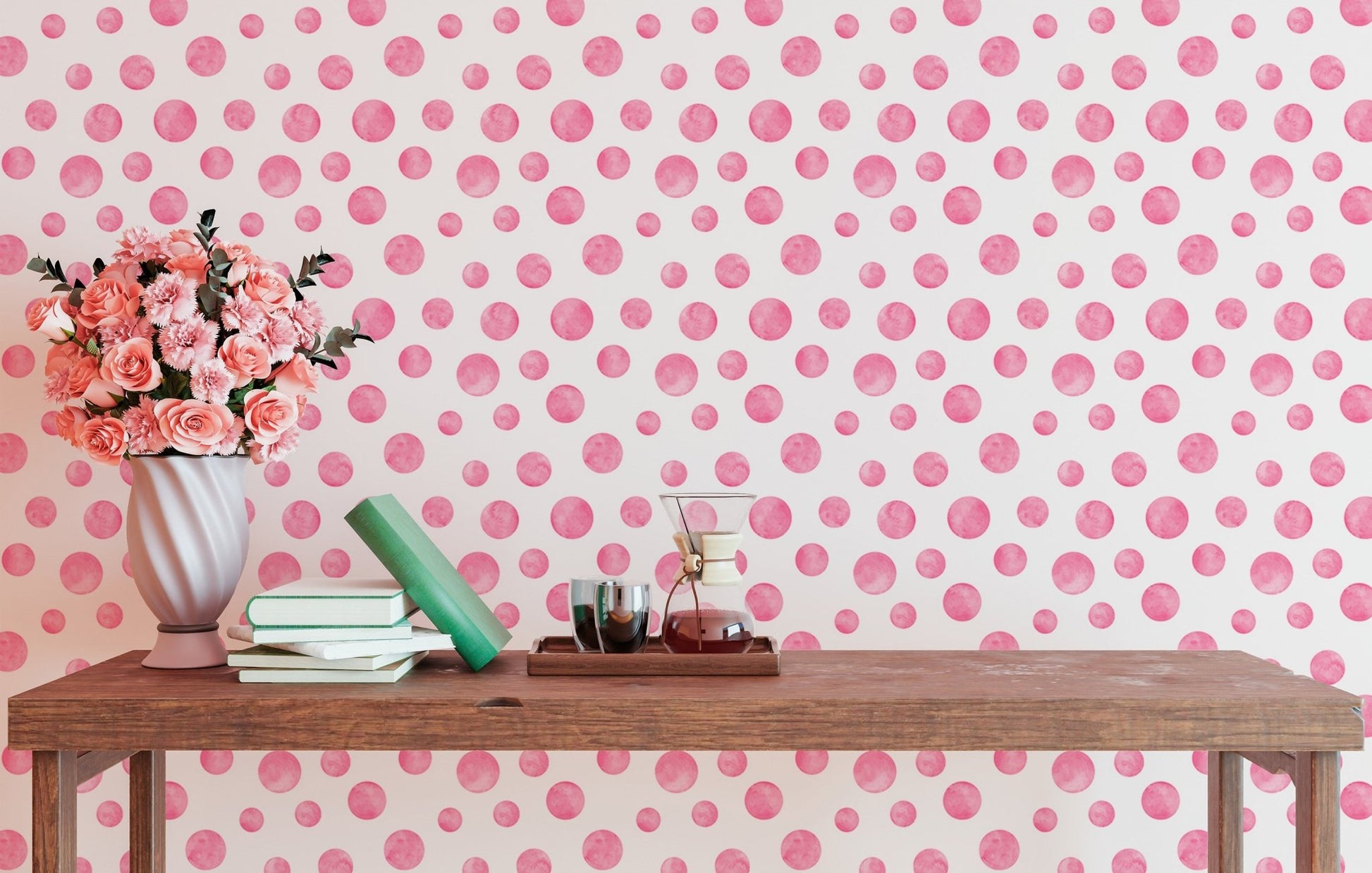 Pink abstract circles wallpaper styled with pink flowers on a wooden desk.