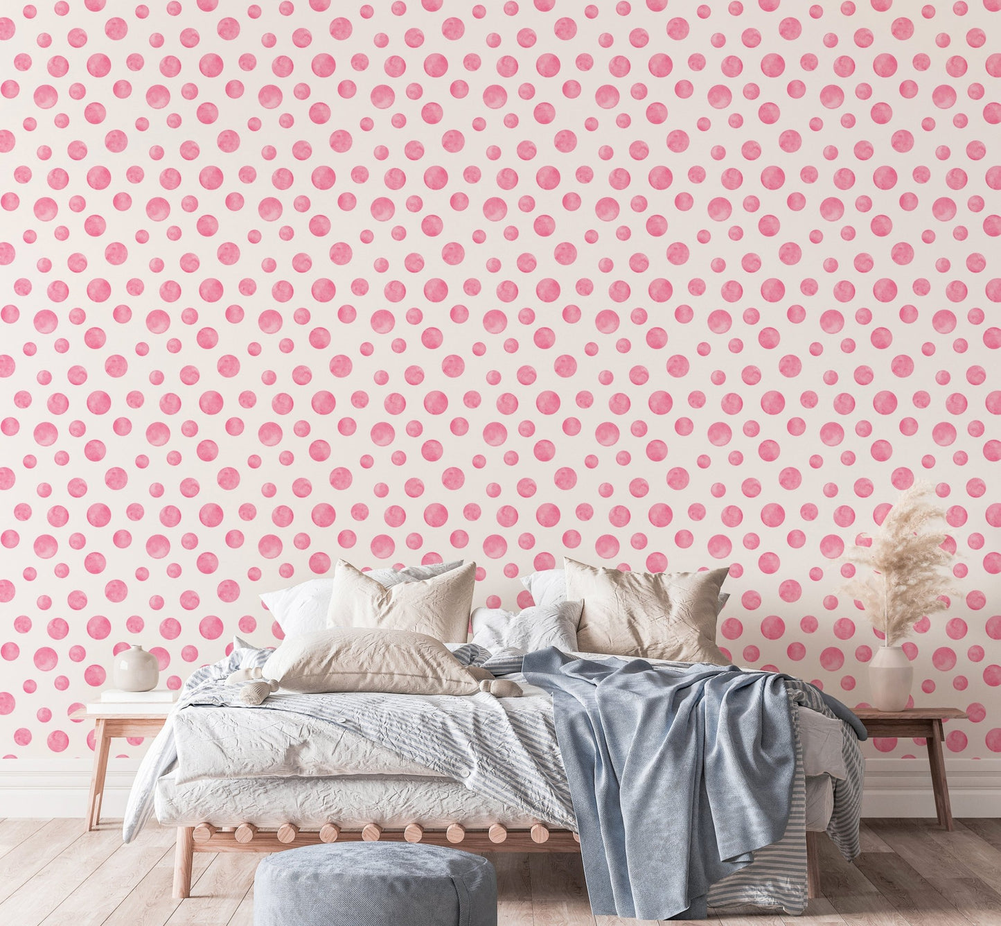 Pink dots wallpaper behind a bed with blue and white linens.