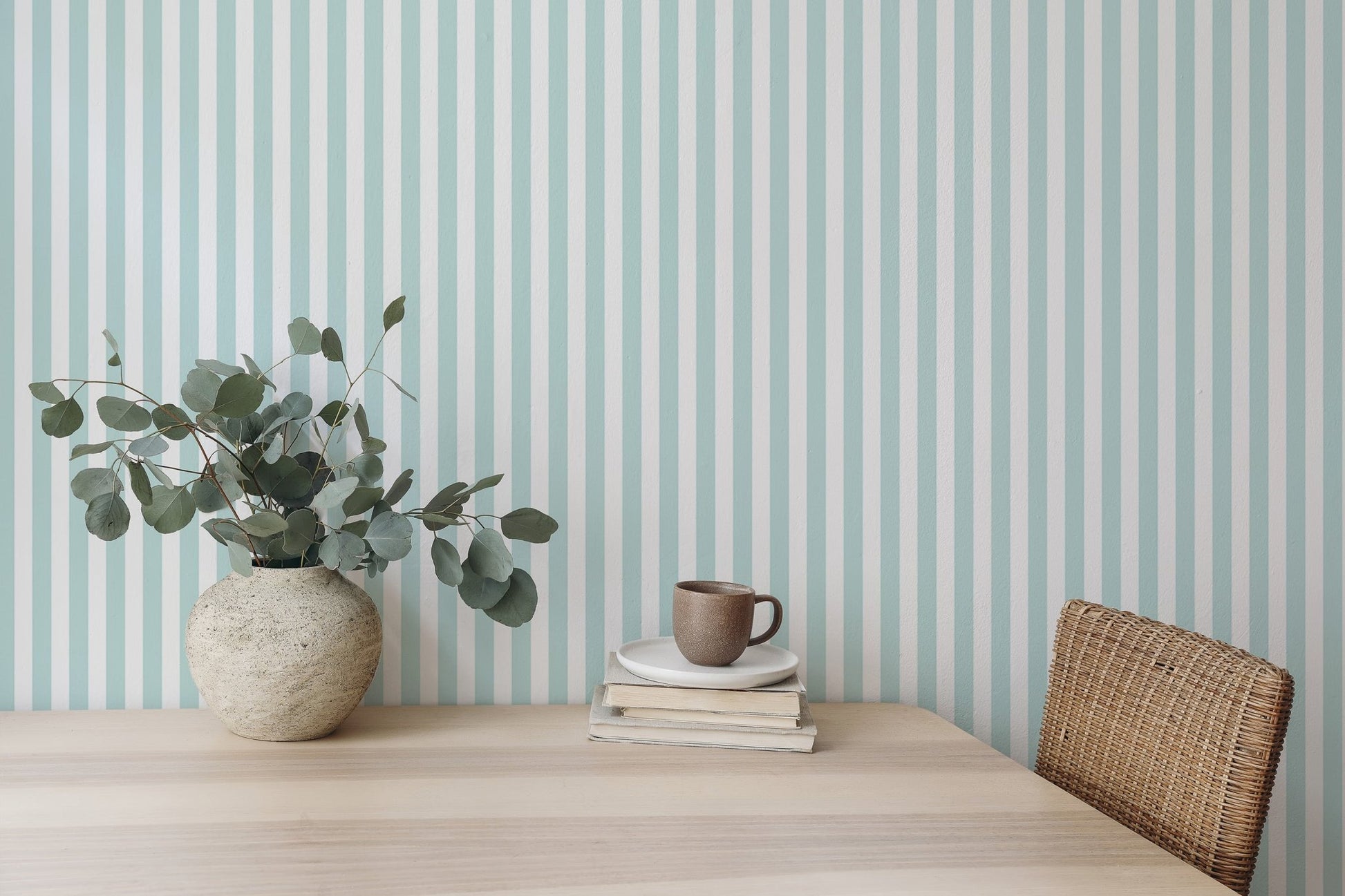 Simple wooden desk setup against a turquoise and white striped wallpaper background.