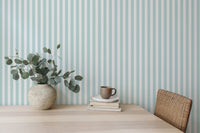 Simple wooden desk setup against a turquoise and white striped wallpaper background.