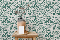 Green floral wallpaper with rabbits behind a wooden stool and clay vase.
