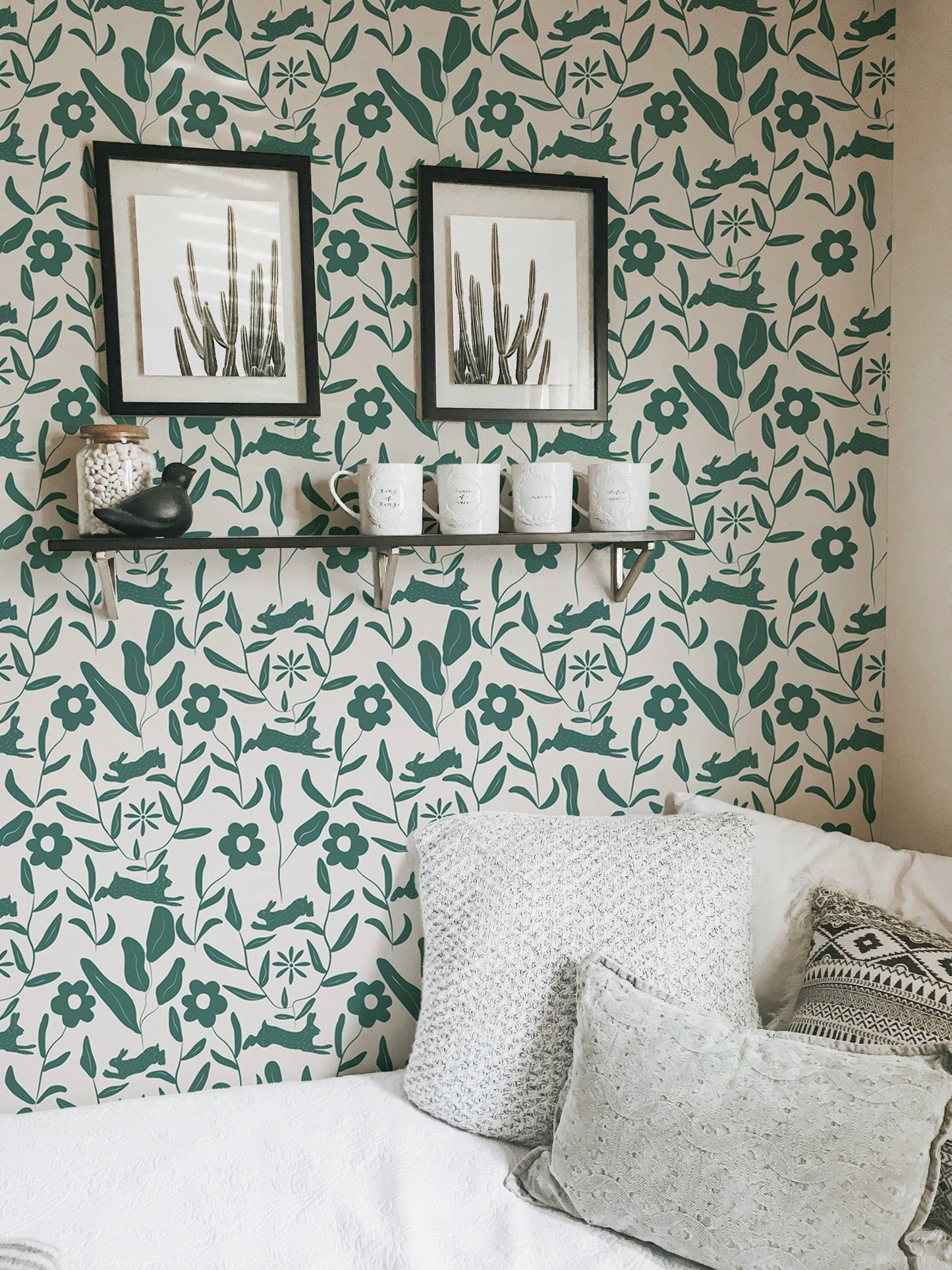Green leaf and flower wallpaper in a workspace with black framed art.