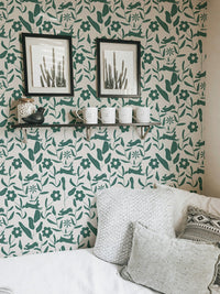 Green leaf and flower wallpaper in a workspace with black framed art.