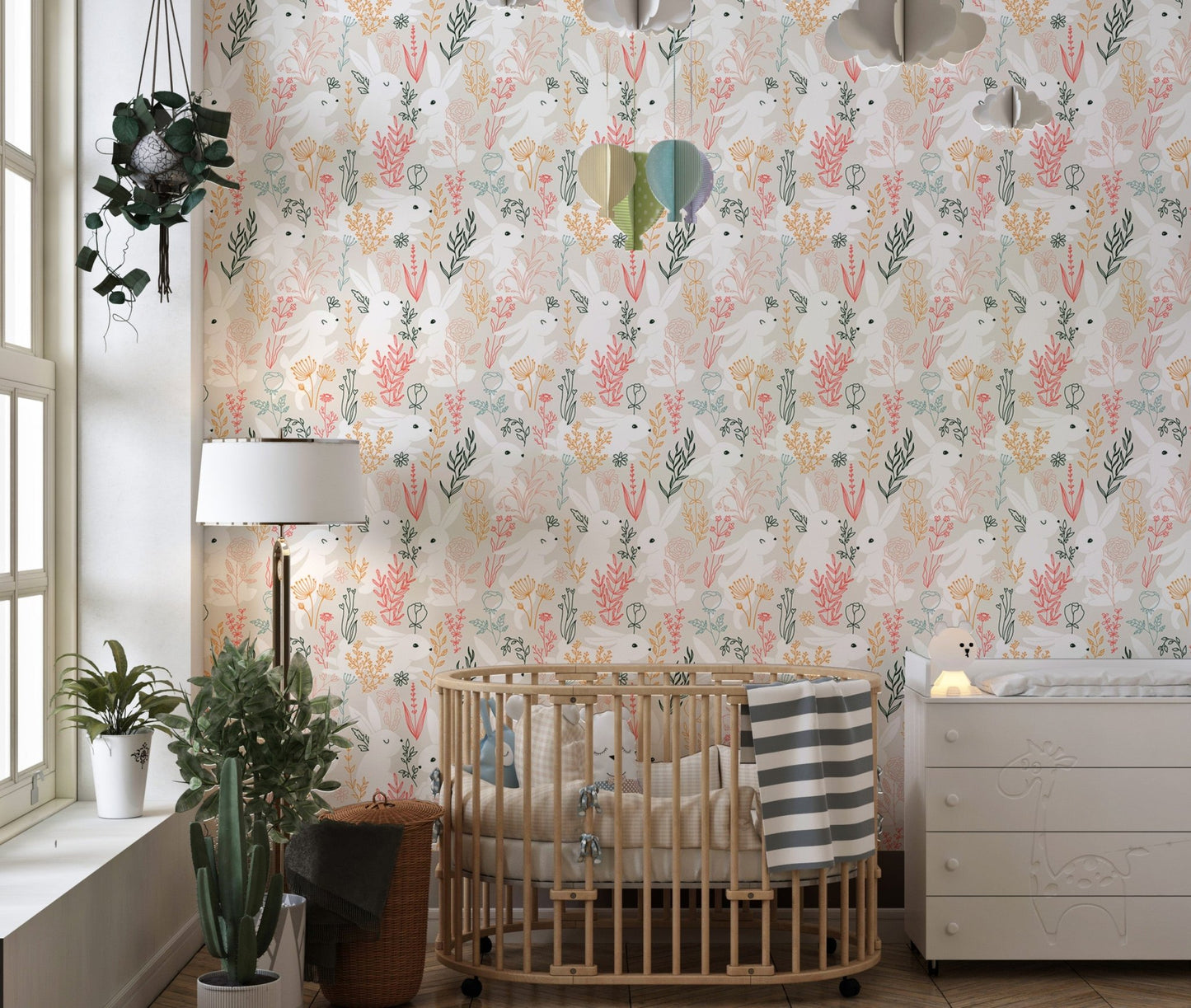 Nursery wallpaper with rabbit and leaf pattern behind a wooden crib.