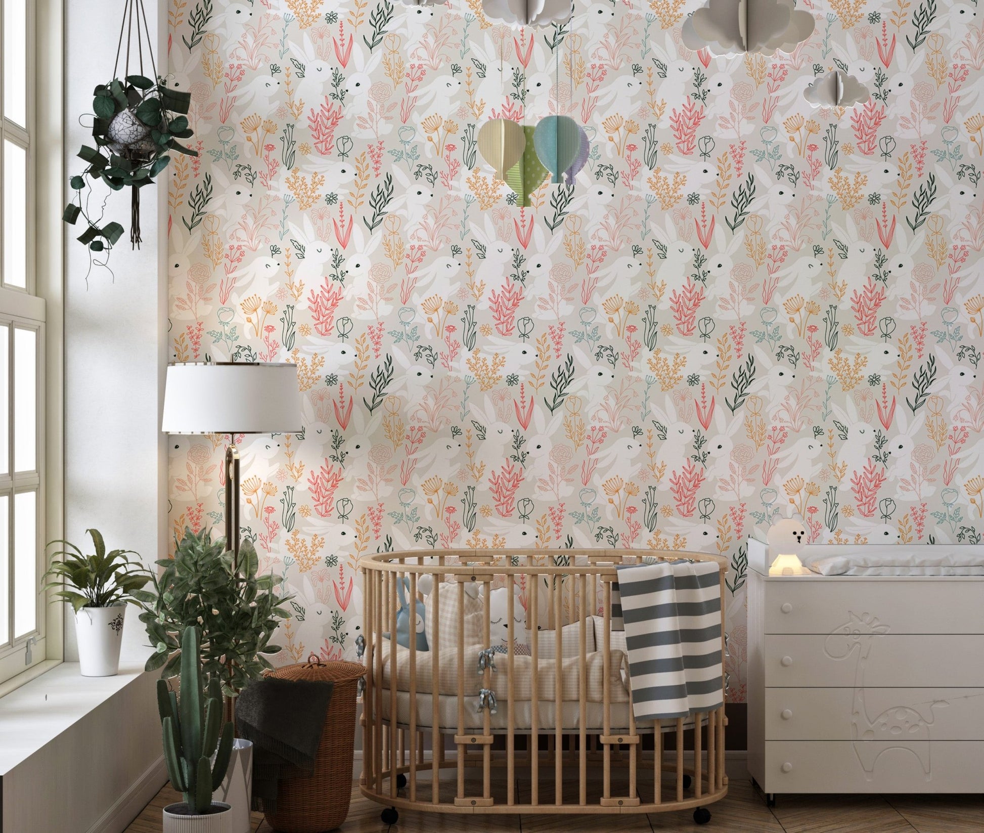 Nursery wallpaper with rabbit and leaf pattern behind a wooden crib.