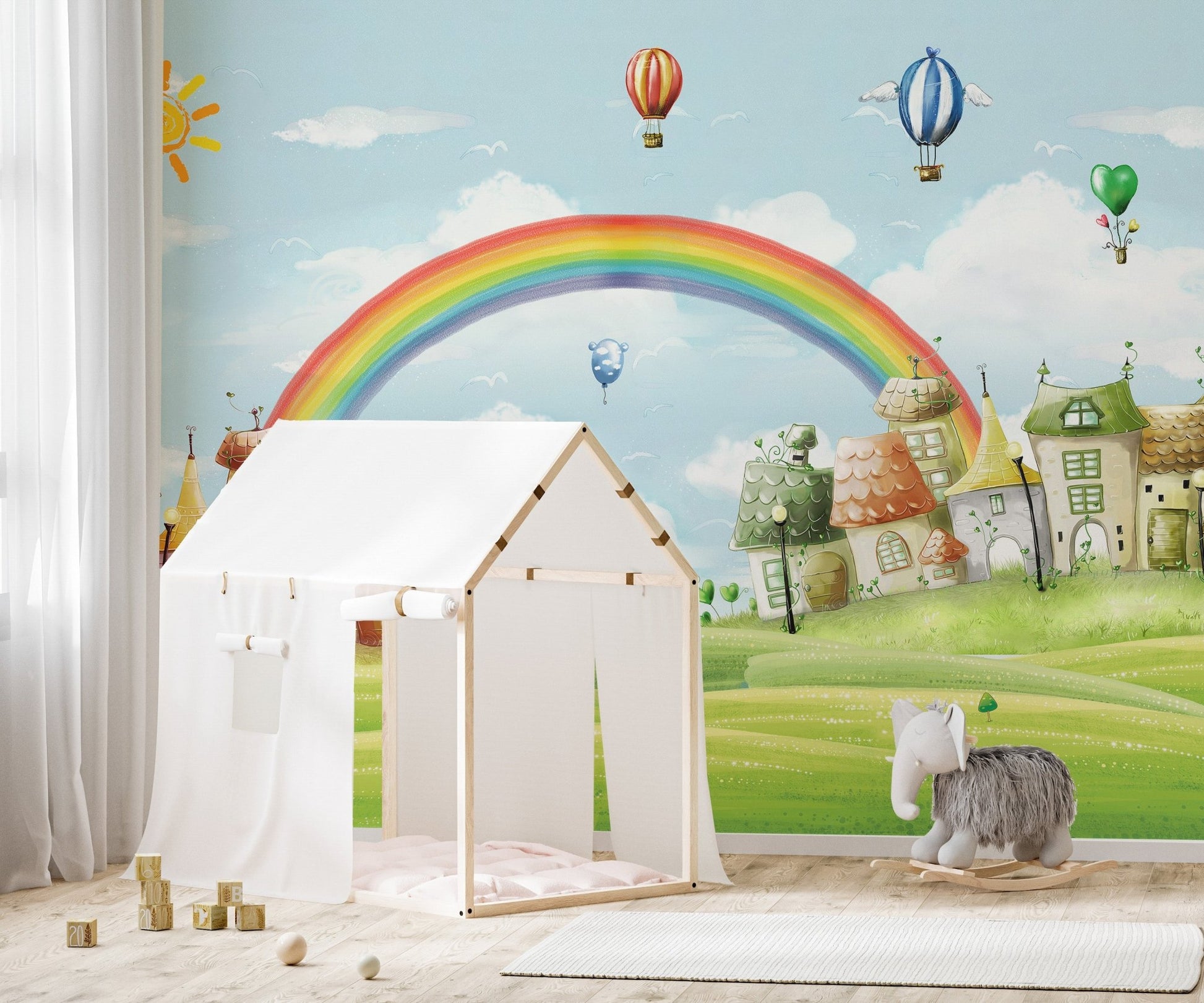 Rainbow and city wall mural behind a white house-shaped play tent for kids.