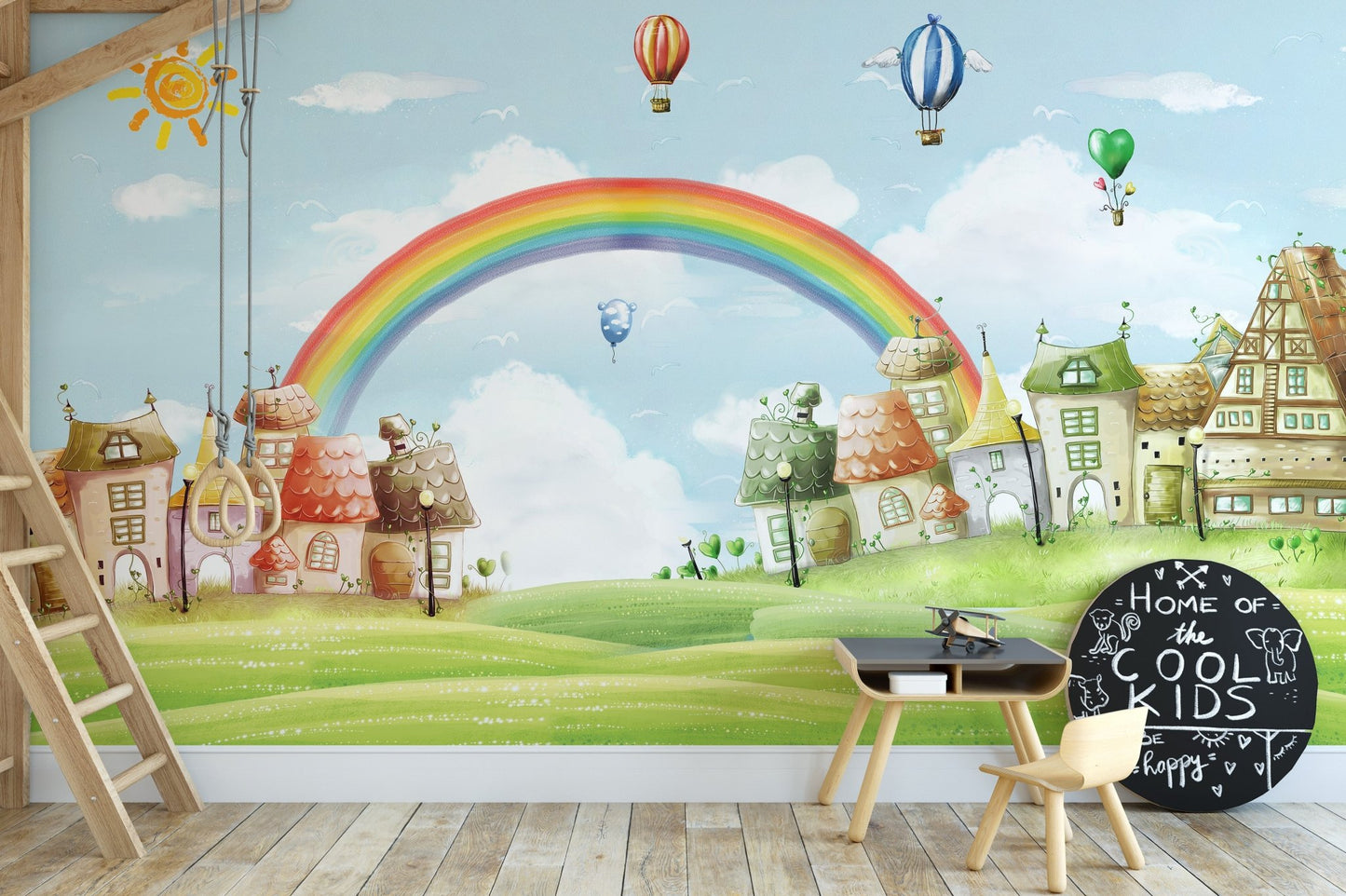Whimsical landscape rainbow wall mural in a study area with a small wooden desk and chair.