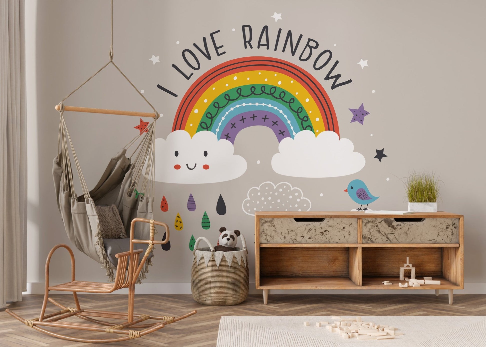 Kids nursery with rainbow wall mural and white wooden storage furniture on a rug.