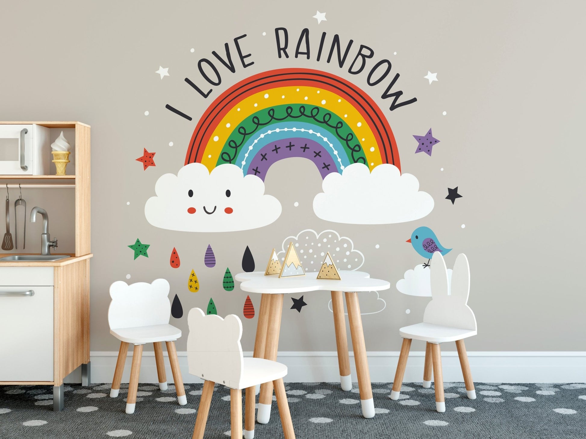 Small wooden table and chairs set against a rainbow wall mural in a homeschool room.