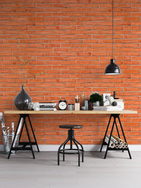 Industrial red brick wallpaper in a home office with a black desk lamp.