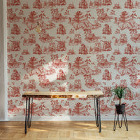 Red chinoiserie wallpaper in a home office with a minimalist desk and plants.