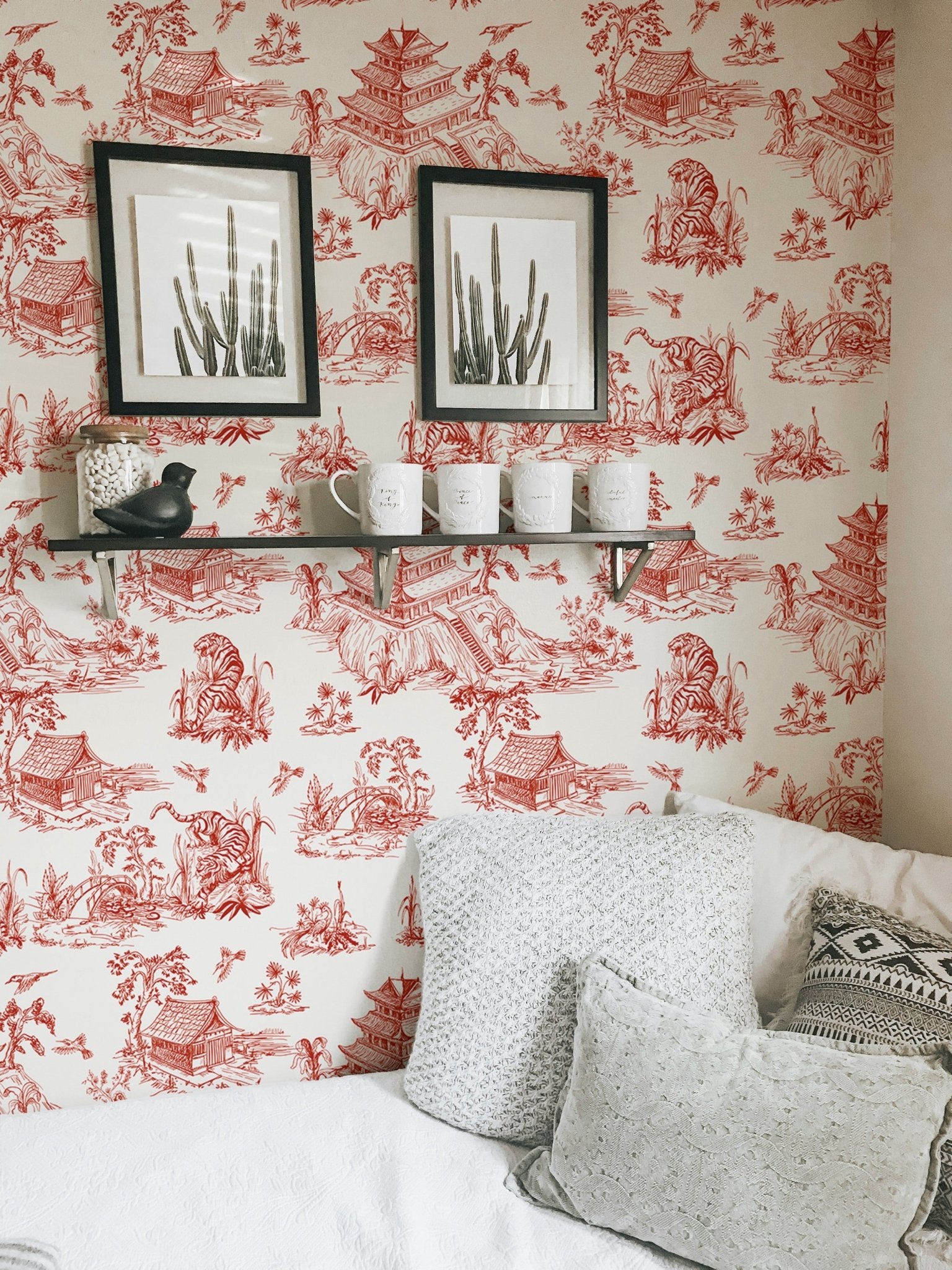Red chinoiserie wallpaper in a home with a minimalist sofa and frame.