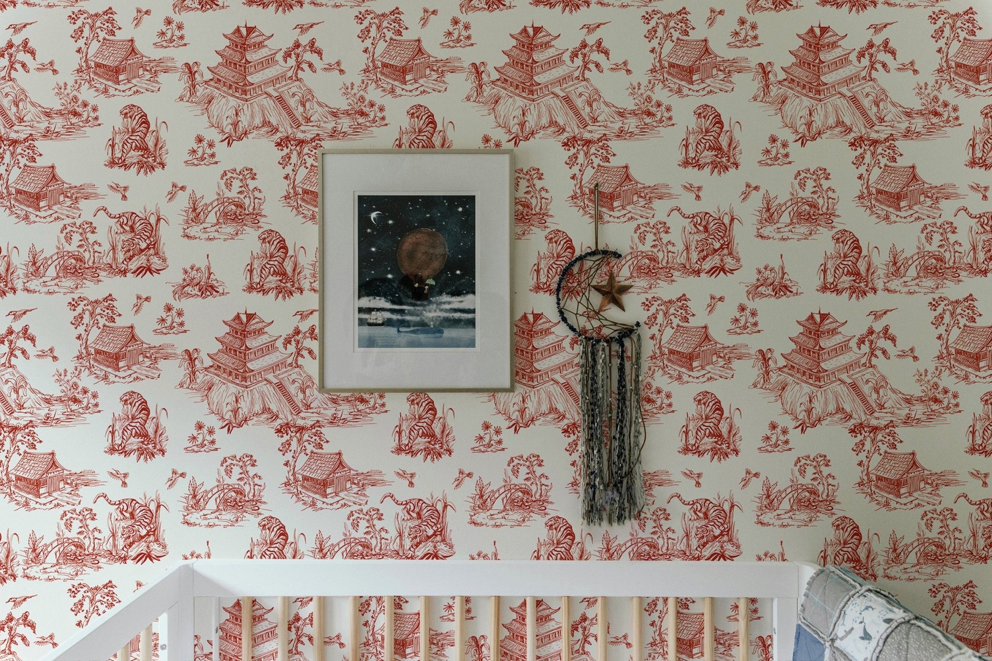 Bedroom wall featuring red chinoiserie wallpaper and framed art.