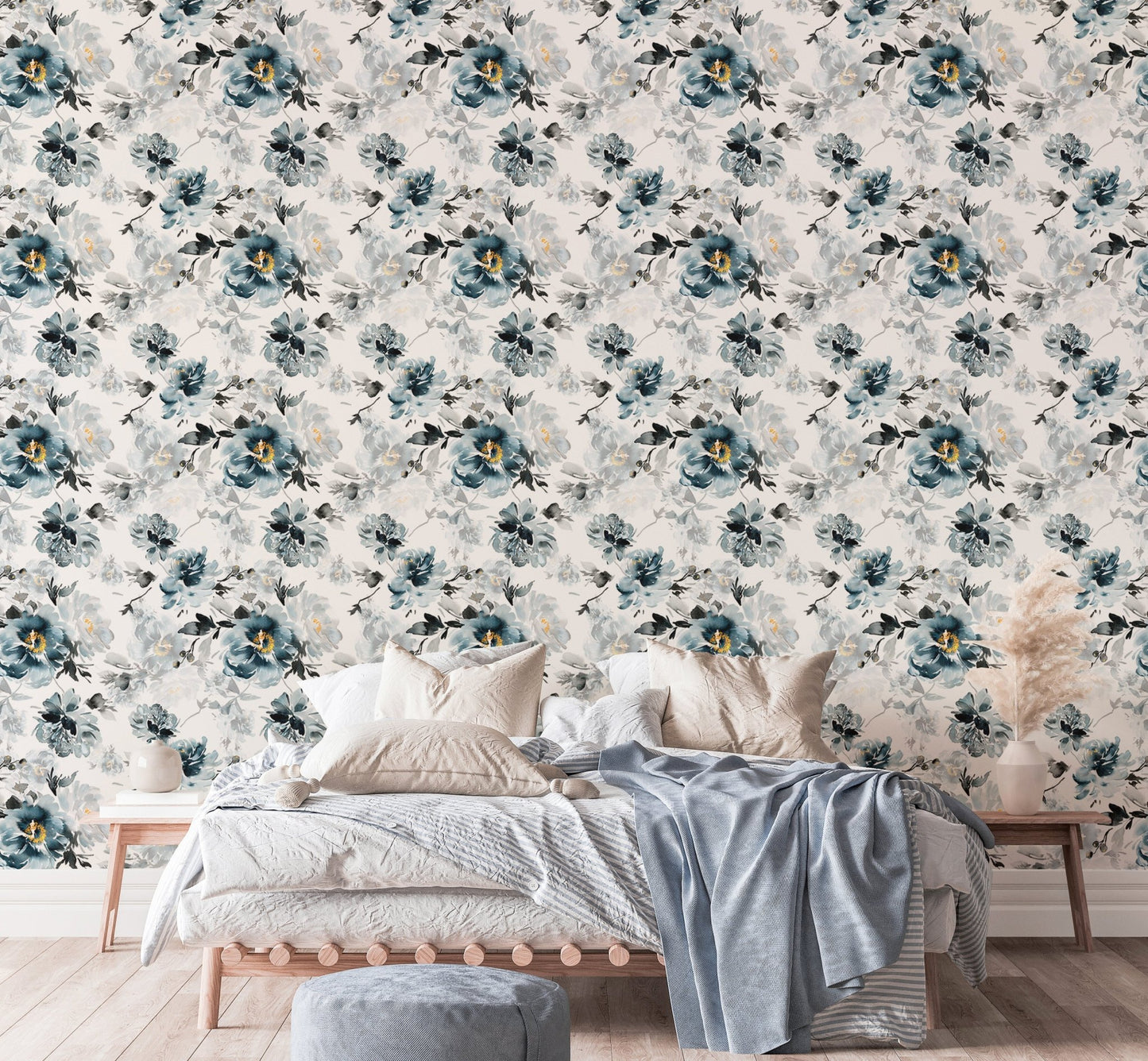 Watercolor floral wallpaper behind a bed with blue cushions and a grey throw.