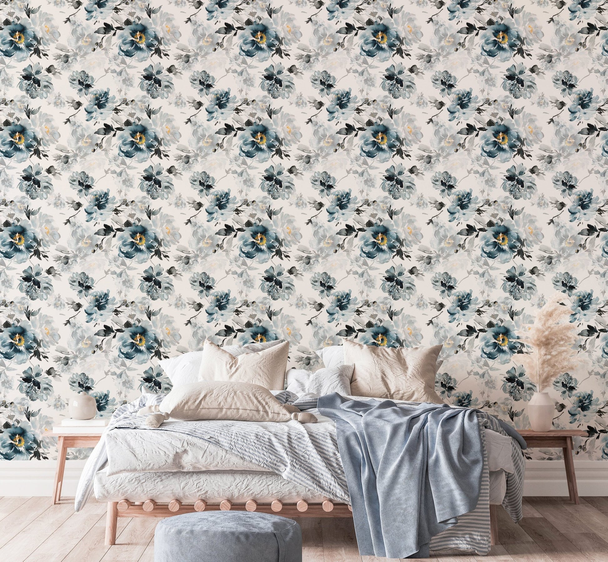 Watercolor floral wallpaper behind a bed with blue cushions and a grey throw.
