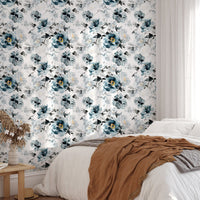 Floral wallpaper with blue watercolor patterns in a bedroom with a tan blanket.