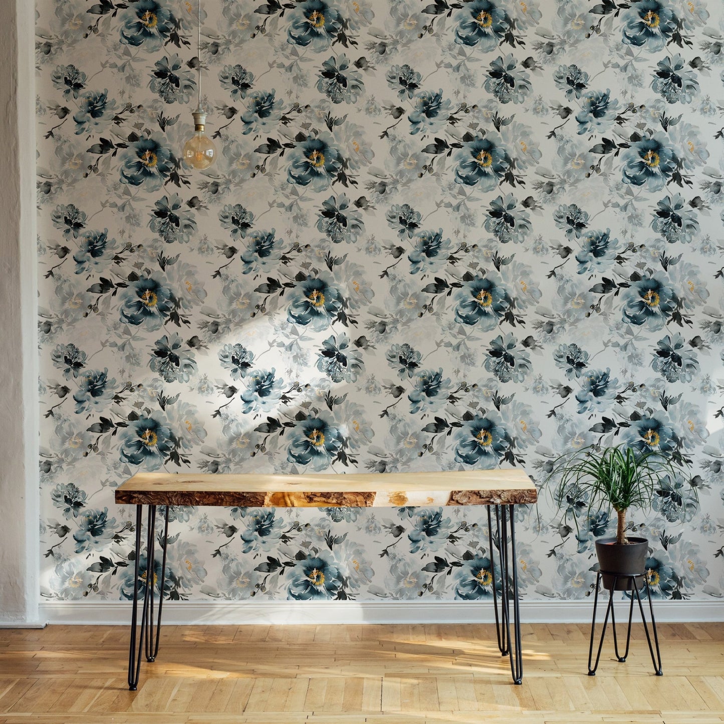 Blue indigo floral wallpaper behind a slim wooden desk and black metal chair.