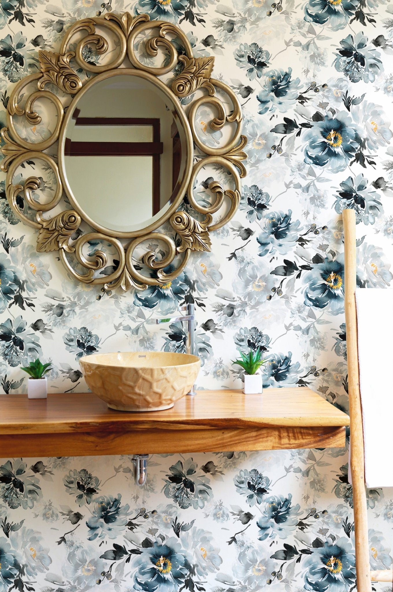 Floral wallpaper featuring indigo blooms behind a wooden shelf and circular mirror.