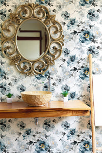 Floral wallpaper featuring indigo blooms behind a wooden shelf and circular mirror.