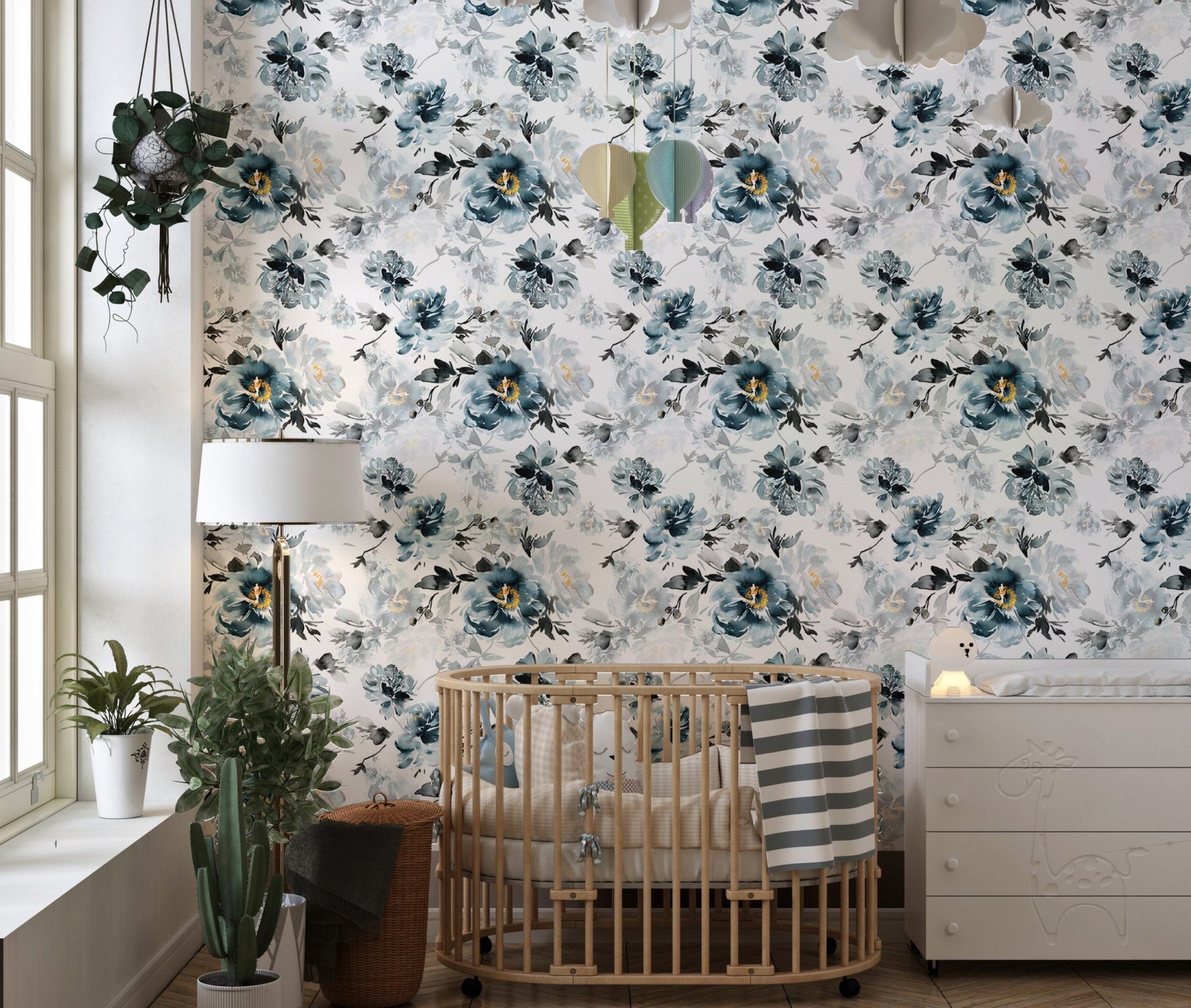 Watercolor flower wallpaper in a nursery with a wooden crib and white dresser.