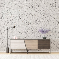 White terrazzo wallpaper behind a modern sideboard with purple flowers.