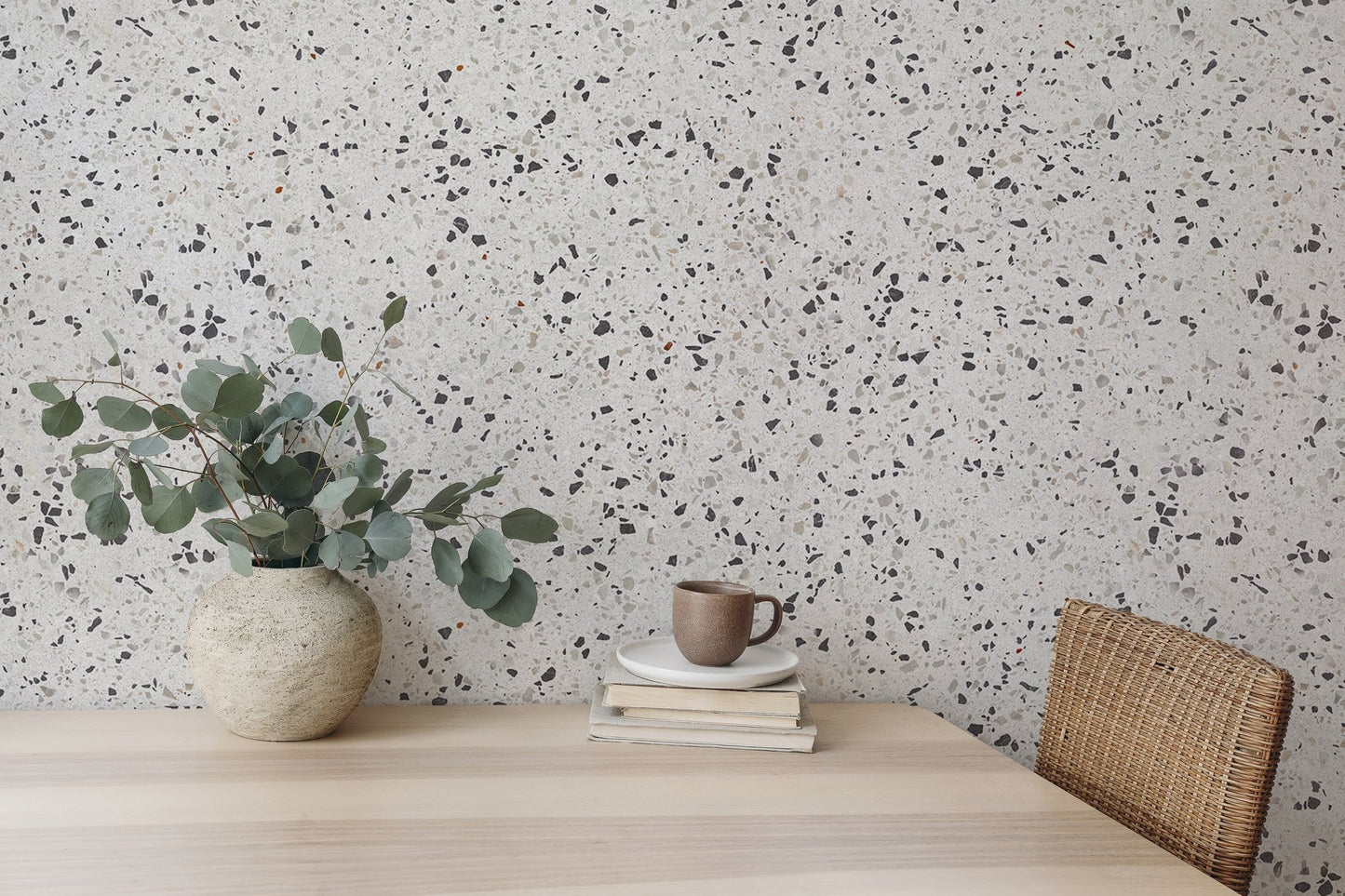 Terrazzo wallpaper pattern behind a wooden dining table and green plants.