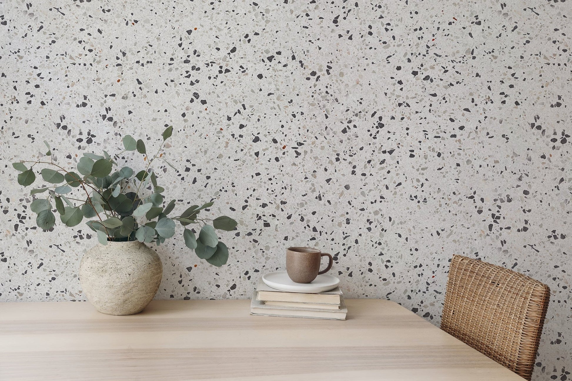 Terrazzo wallpaper pattern behind a wooden dining table and green plants.