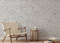 Stone texture wallpaper in reading space with a wooden chair and side table.