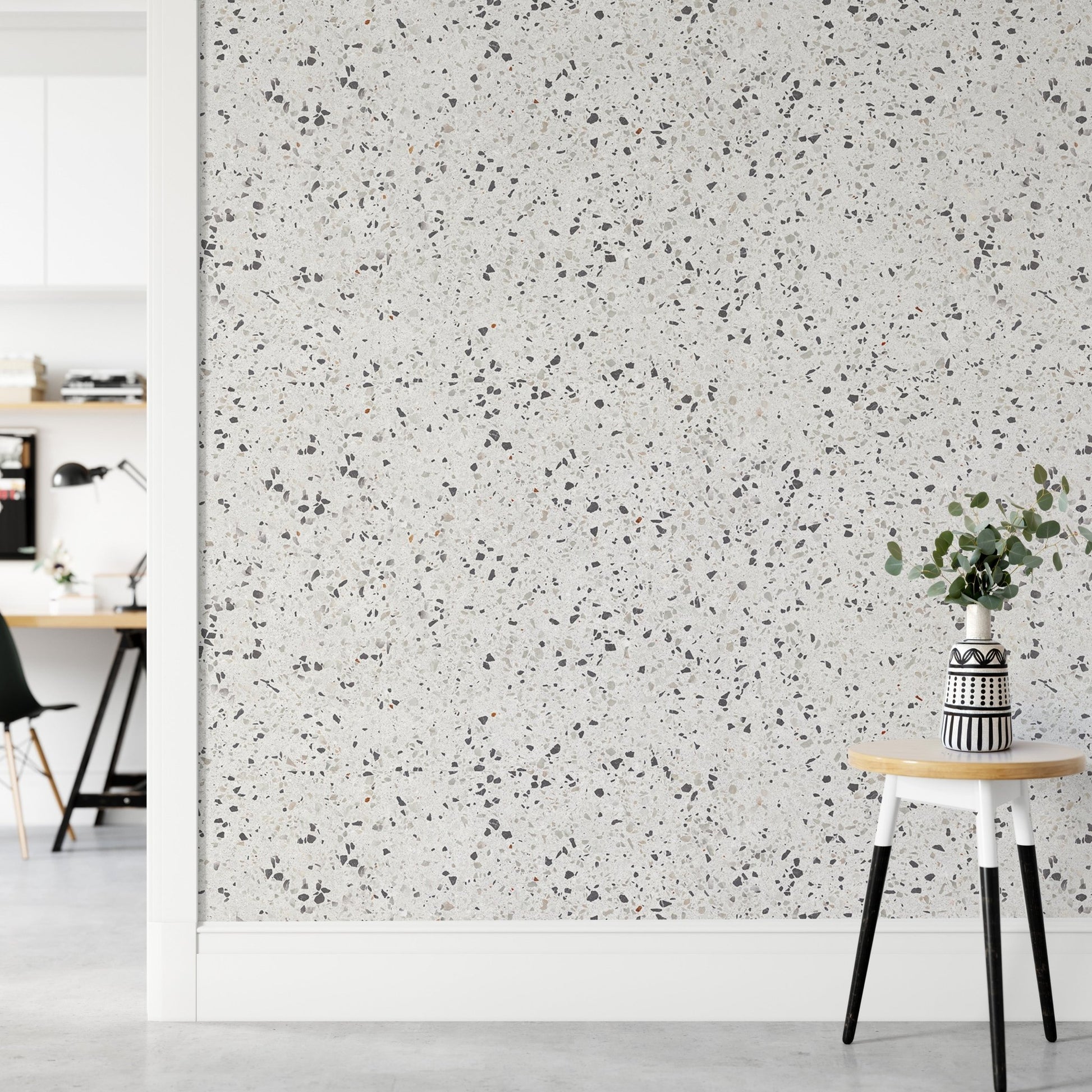 Neutral terrazzo wallpaper in a hallway next to a small white stool.