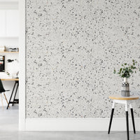 Neutral terrazzo wallpaper in a hallway next to a small white stool.