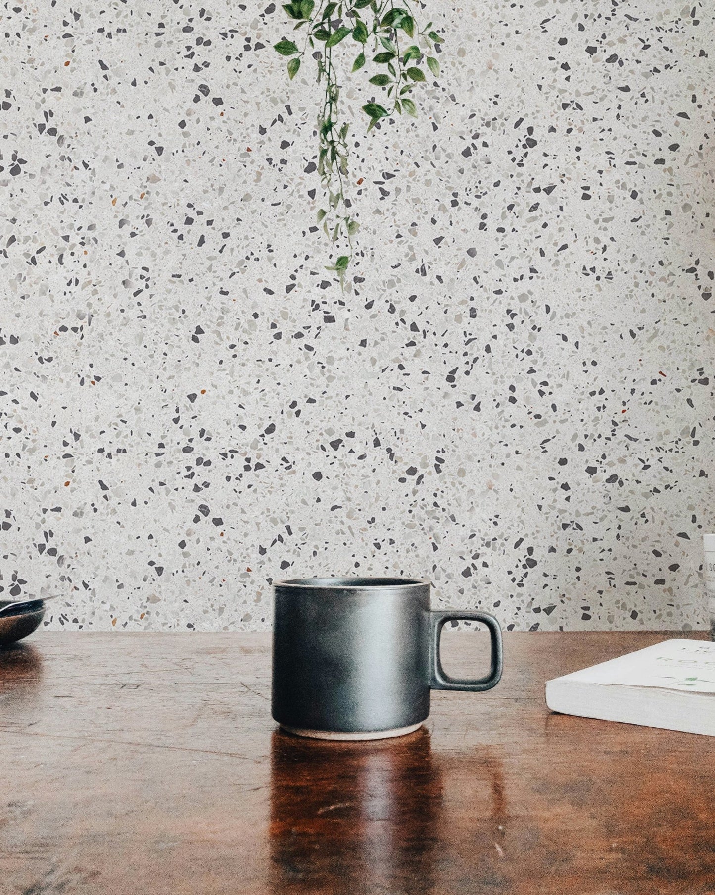 Repeat Pattern Terrazzo Designs White Texture Wallpaper behind a dark coffee mug.