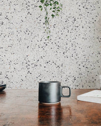 Repeat Pattern Terrazzo Designs White Texture Wallpaper behind a dark coffee mug.