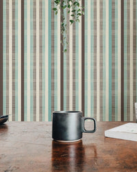 Vertical green and brown striped wallpaper behind a wooden desk and black mug.