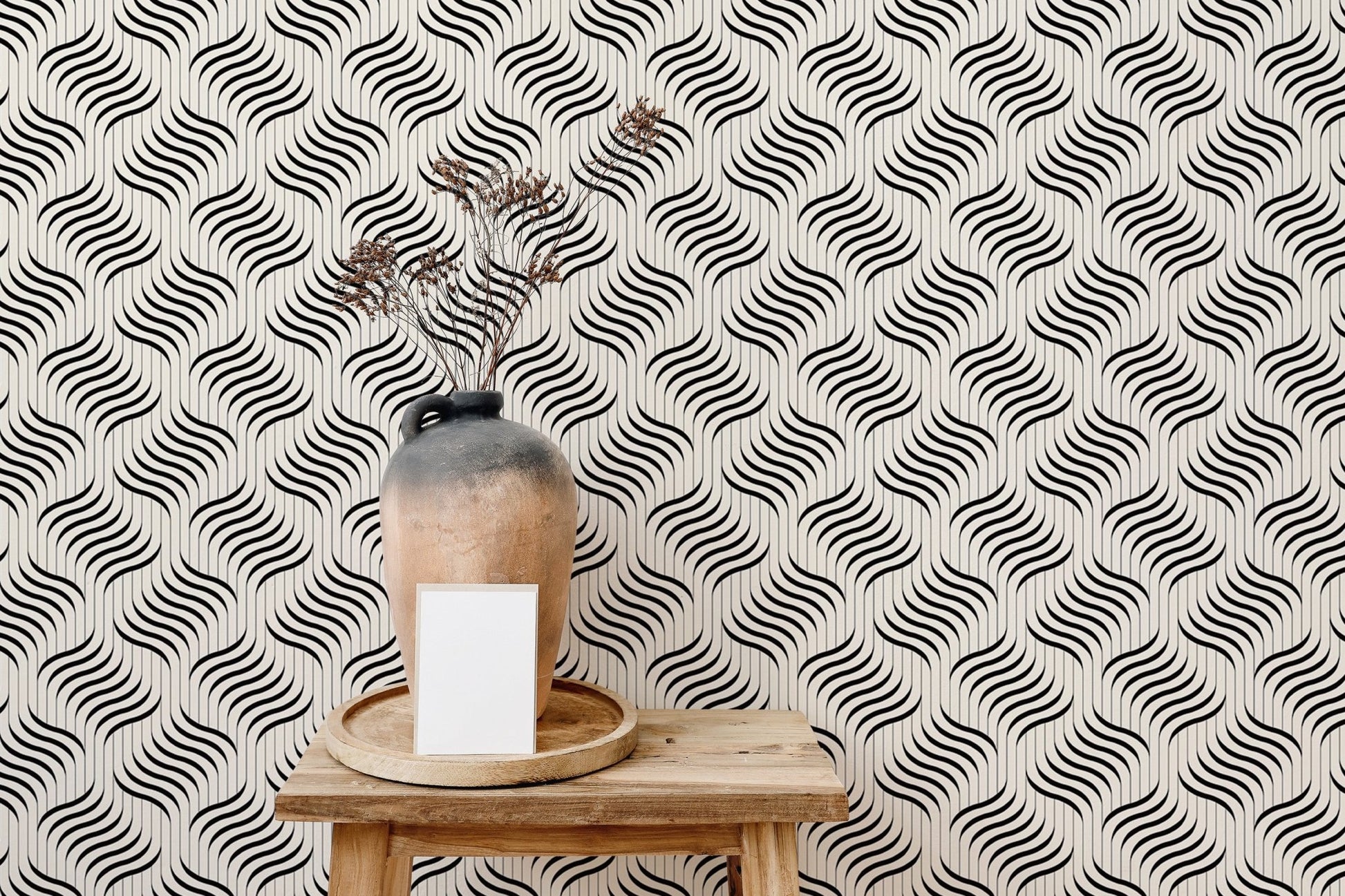 Monochrome ripple wallpaper behind a ceramic vase on a wooden stool.