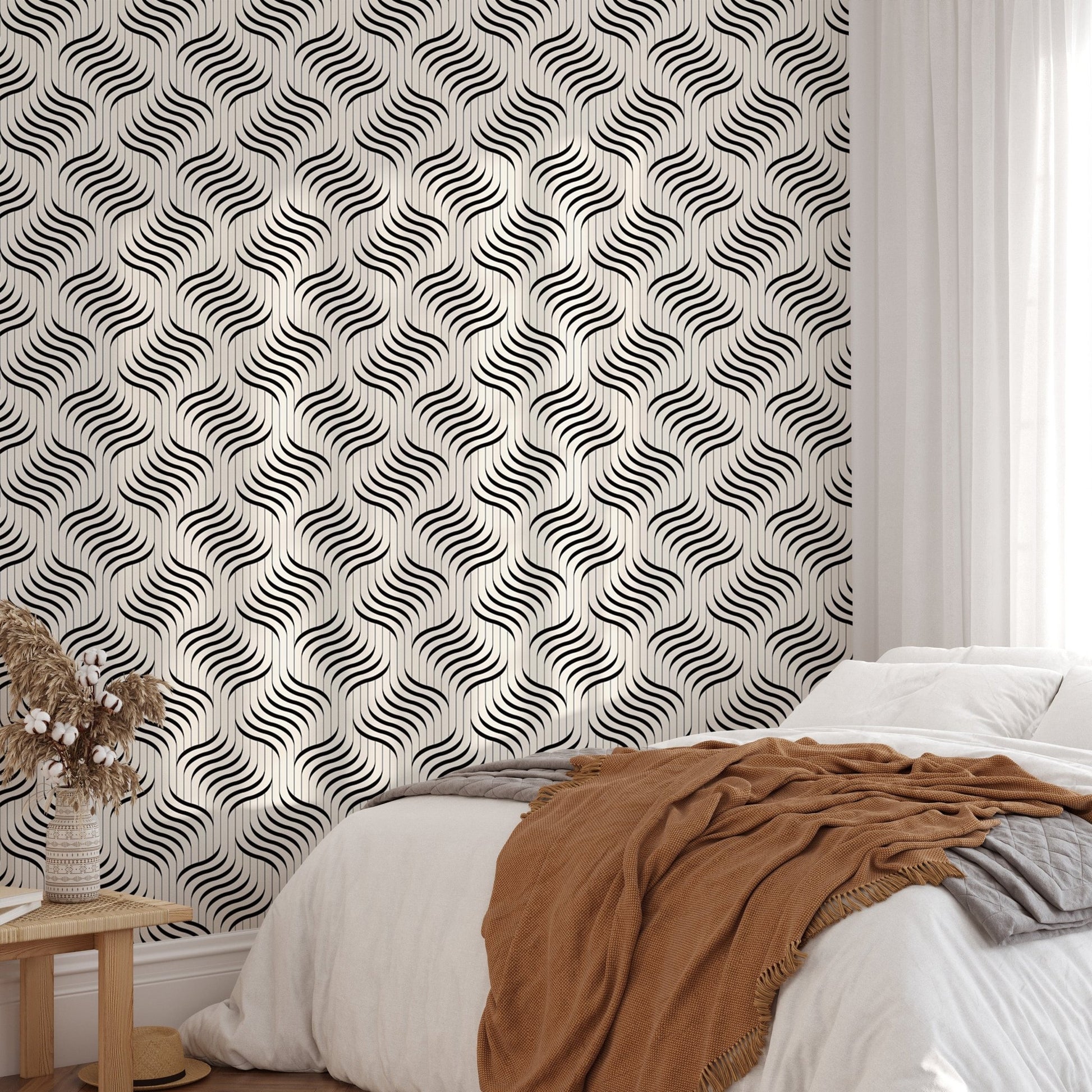 Monochrome ripple wallpaper behind a bed with a brown throw blanket.