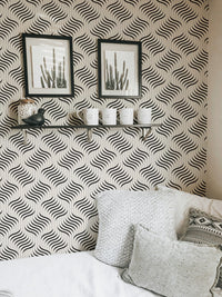 Abstract geometric wallpaper in a bright room with a shelf and framed art.