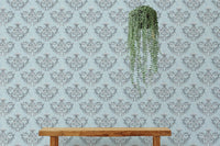 Textured floral wallpaper behind a wooden bench with hanging plants.