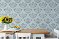 Grey floral wallpaper behind a dining table with yellow flowers in a vase.