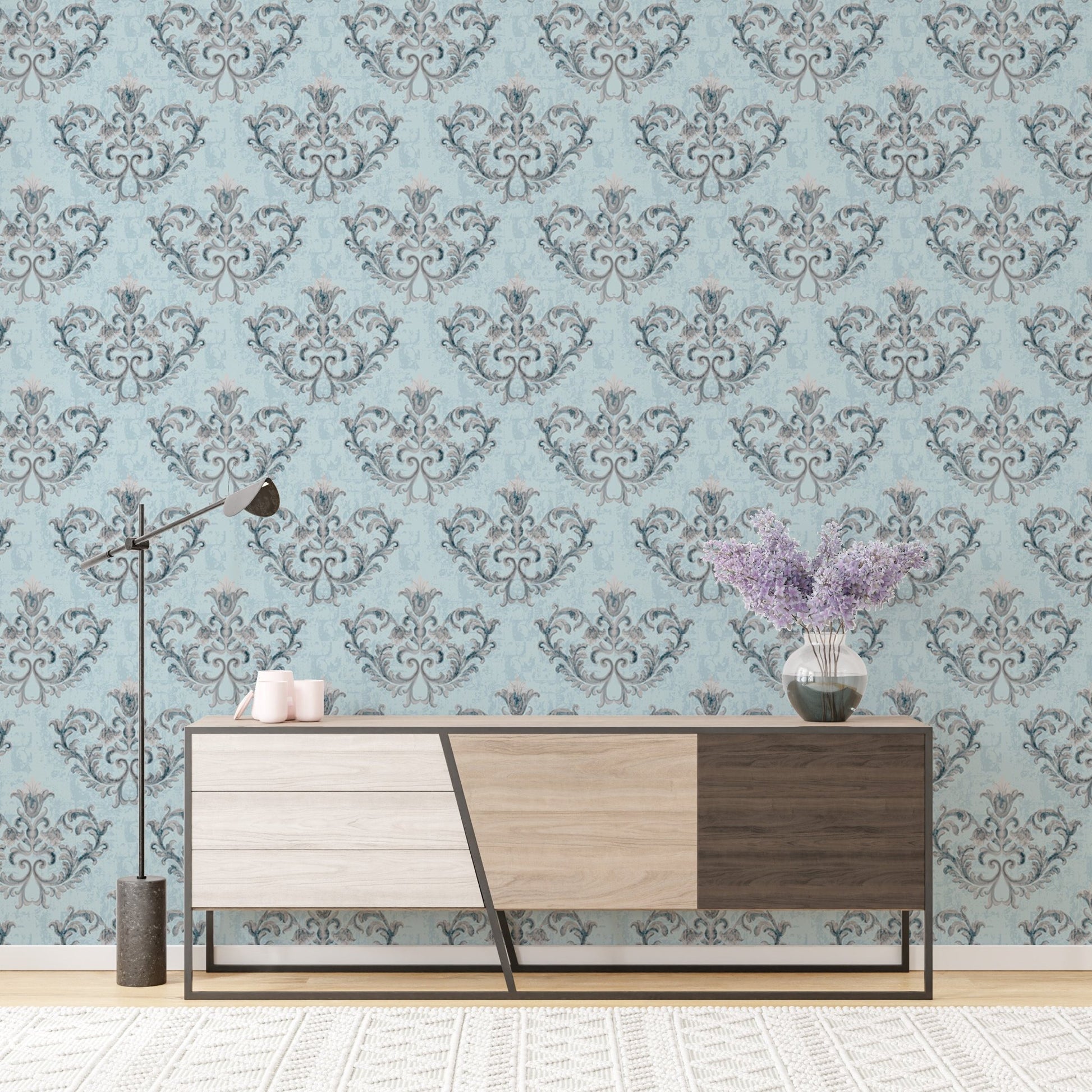 Blue damask wallpaper behind a modern wooden sideboard with grey drawers.