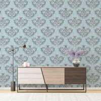 Blue damask wallpaper behind a modern wooden sideboard with grey drawers.