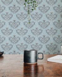 Rococo Silver Texture Pattern Floral Ornaments Wallpaper viewed from a wooden table.