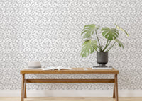 Grey floral wallpaper behind wooden bench and green potted plant.