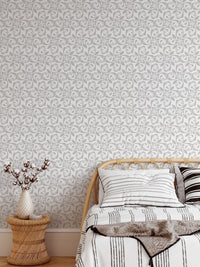 Floral ornament wallpaper in bedroom with wood bed frame and white pillows.