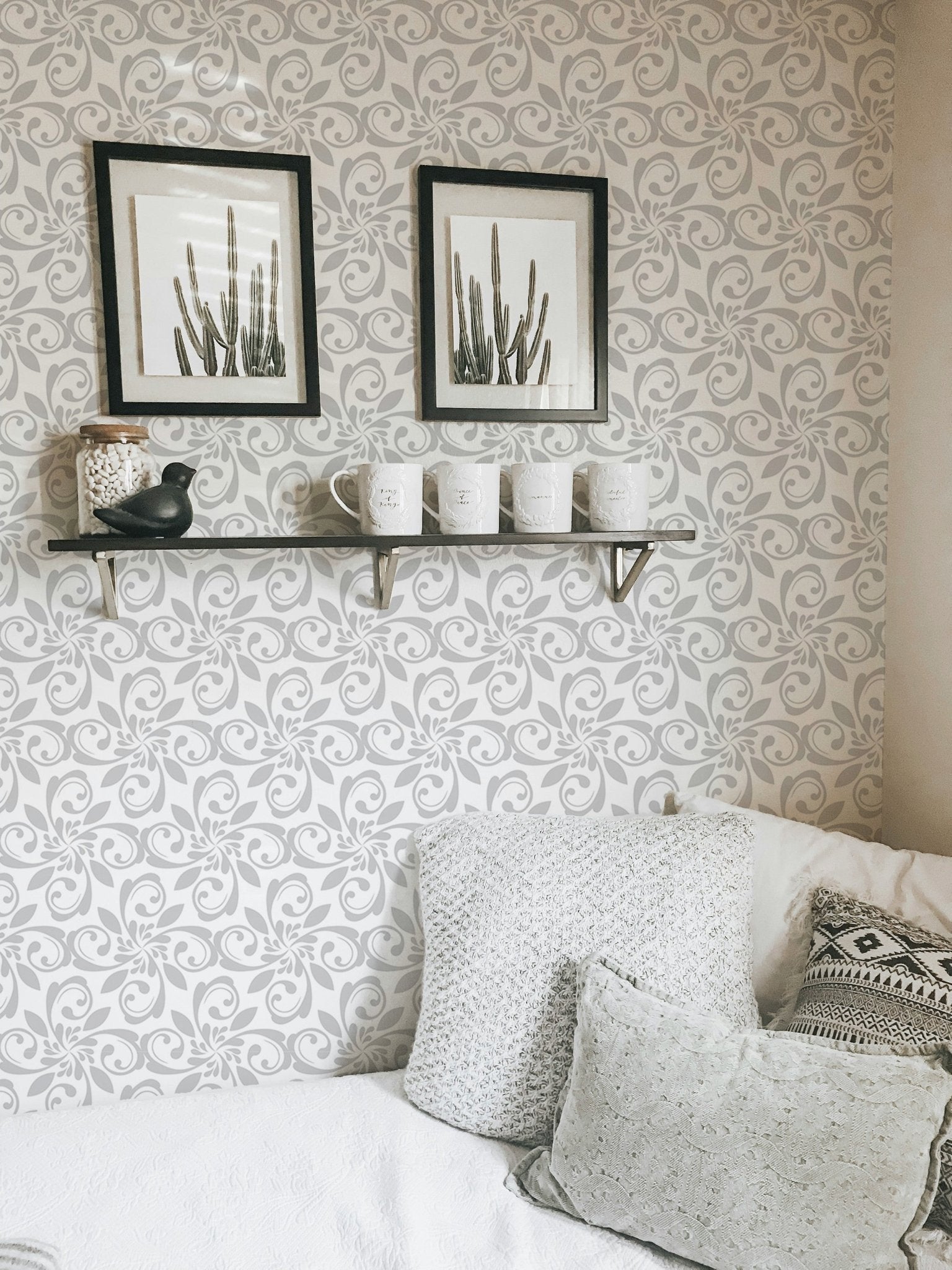 Floral ornament wallpaper behind white sofa and wall shelf with frames.