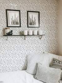 Floral ornament wallpaper behind white sofa and wall shelf with frames.