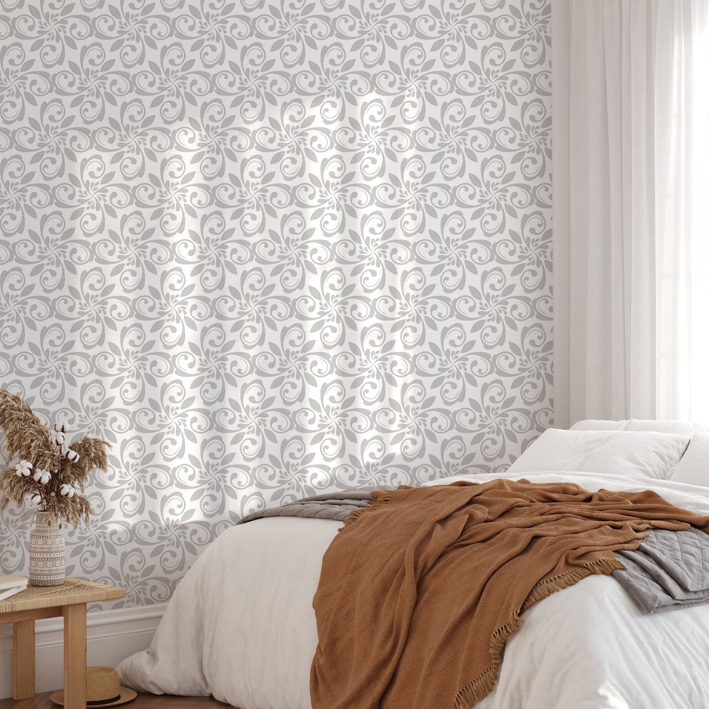 Damask pattern wallpaper on bedroom wall with white bedding and brown throw.