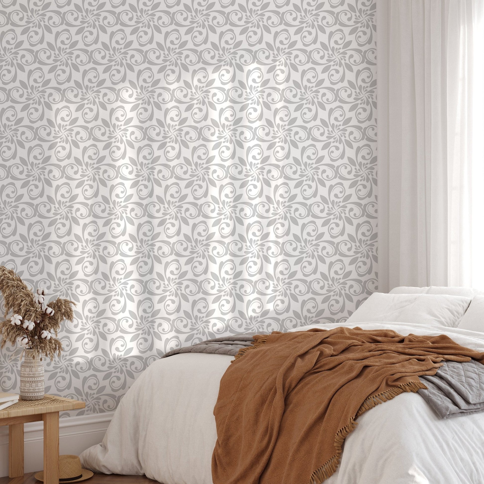 Damask pattern wallpaper on bedroom wall with white bedding and brown throw.